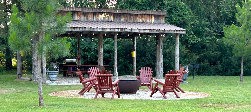 Covered pavilion at Wagon Train RV Park in Canton, Texas with picnic tables, fire pit seating, and space for guests to relax near I-20.